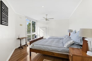 Une chambre à coucher avec un lit, une table de chevet, une lampe et un ventilateur de plafond.