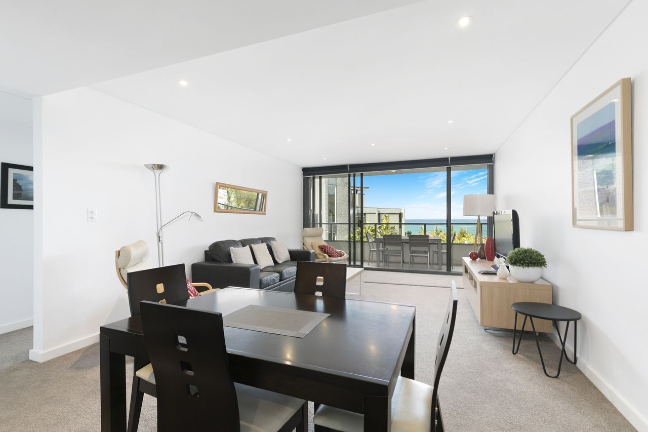Uma sala de estar moderna com área de refeições, um sofá, uma mesa de centro e vista para o exterior.