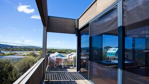 A balcony with a view of a bridge and greenery, furnished with chairs and a table. - Debonair 1 (Anglesea)