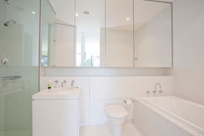A modern bathroom with a glass shower enclosure, a sink with a mirror above, a toilet, and a bathtub.