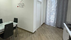A small, well-lit room with a dining table and chairs, a window with sheer curtains, and a wall decal. - Sleeping in Naples Center holiday house holiday home (Napoli)
