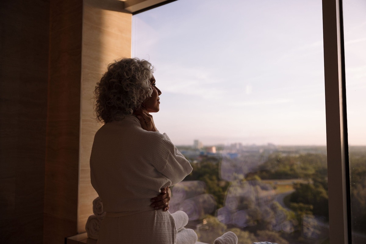 A person sitting by a window overlooking a cityscape.