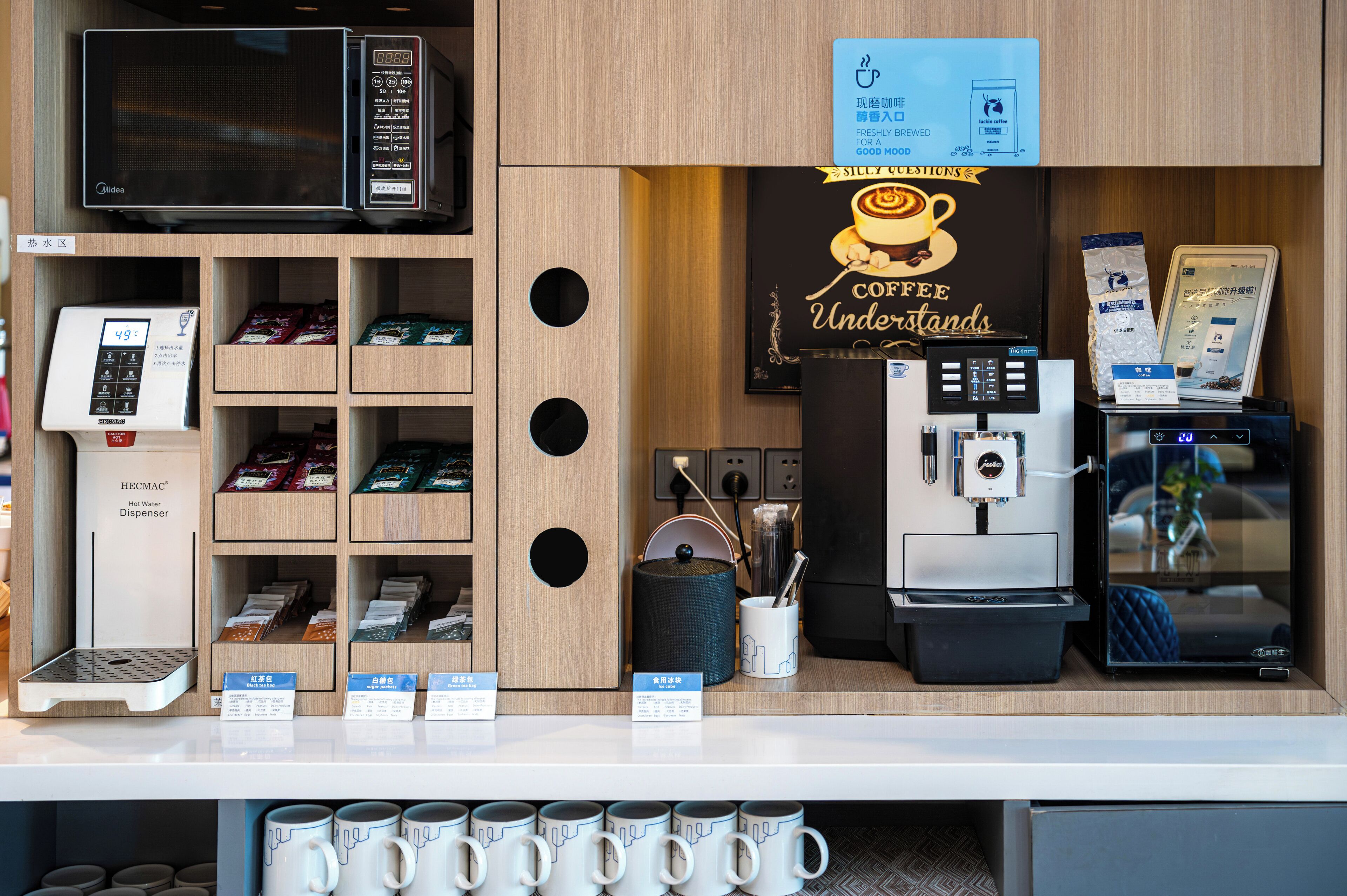 A coffee shop counter with a coffee machine, a hot water dispenser, and various tea and coffee products displayed on shelves.