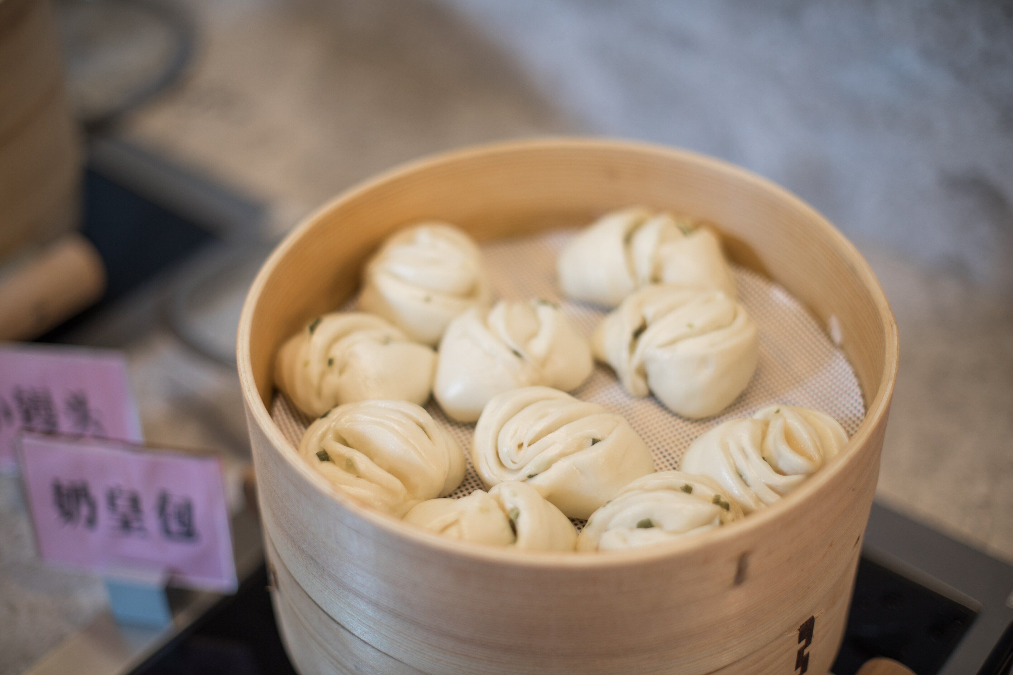 A bamboo steamer with several steamed buns.