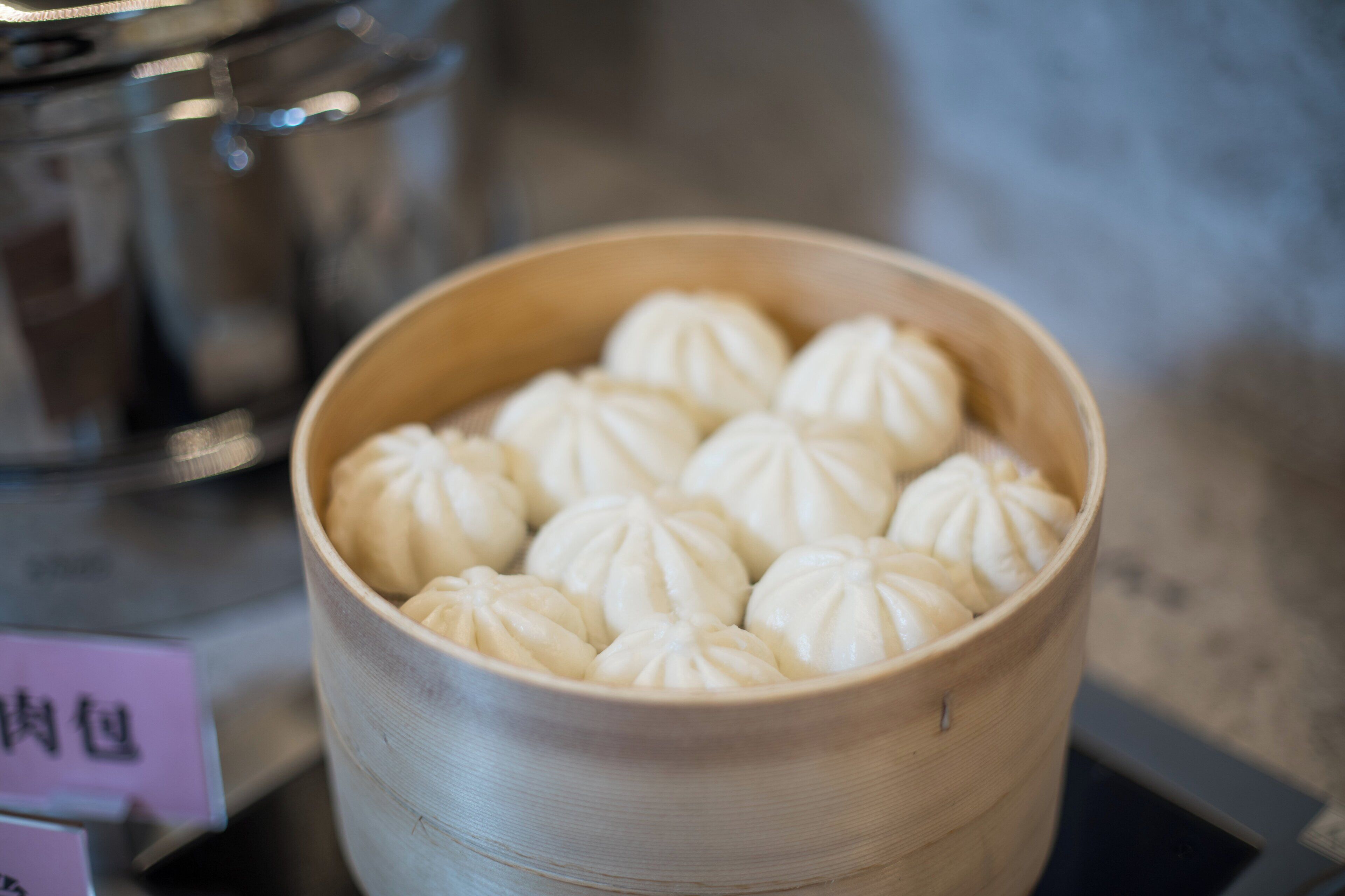 A bamboo steamer with white dumplings.