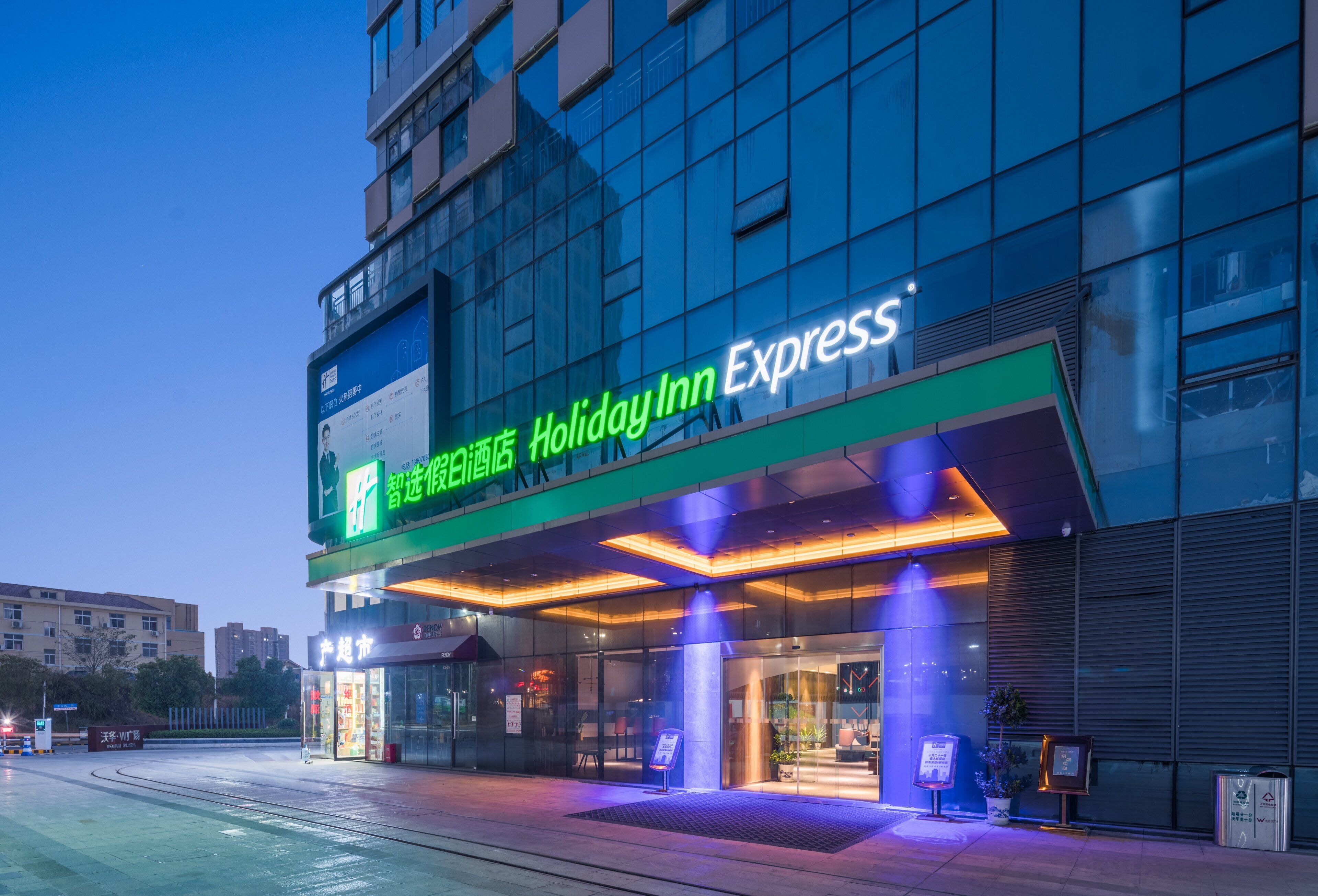 A Holiday Inn Express building with a modern glass facade and illuminated signage.