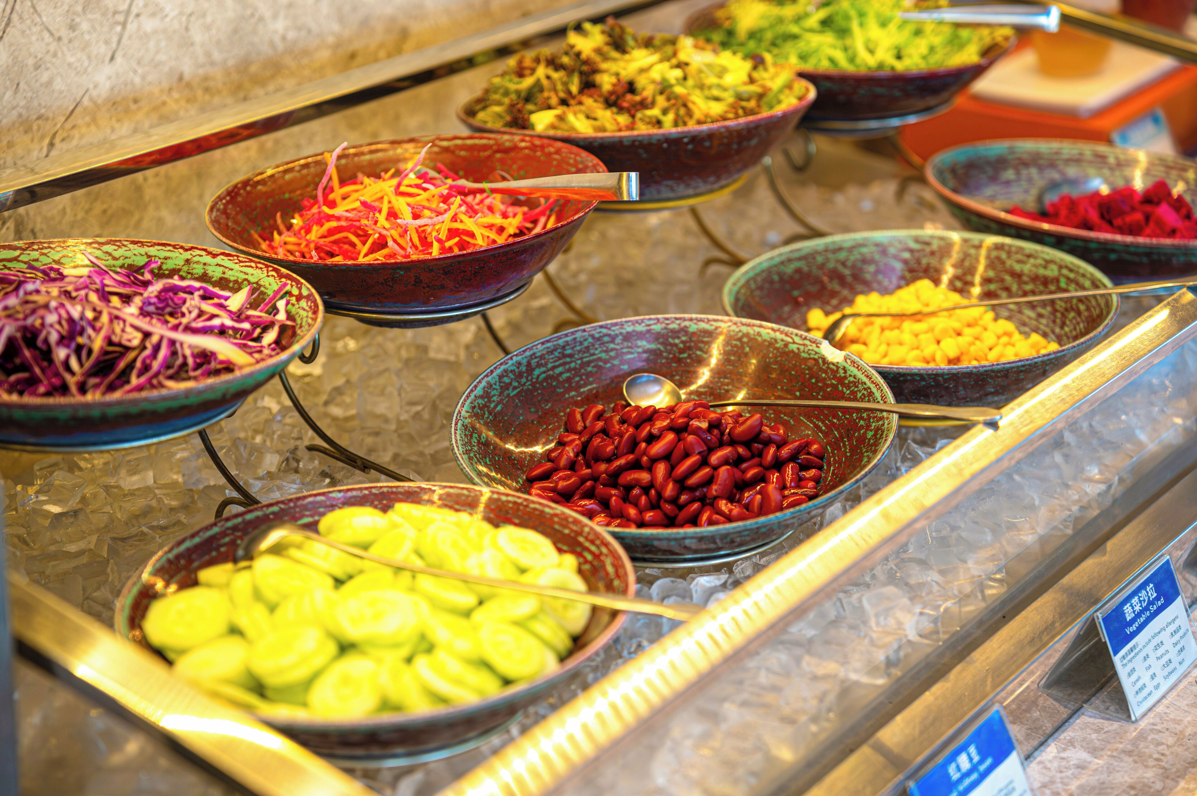 A buffet with various dishes including vegetables, beans, and other prepared foods.