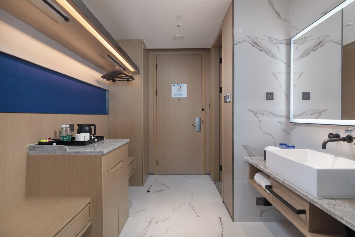 A modern bathroom with a large mirror, a sink, and a shower area.