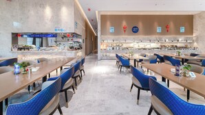 Un restaurant moderne doté d’un comptoir central, de chaises à l’assise bleue et d’un design épuré et contemporain.
