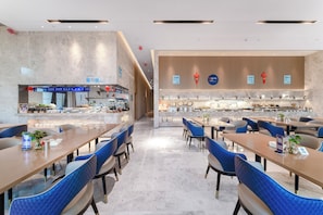 Un restaurant moderne doté d’un comptoir central, de chaises à l’assise bleue et d’un design épuré et contemporain.