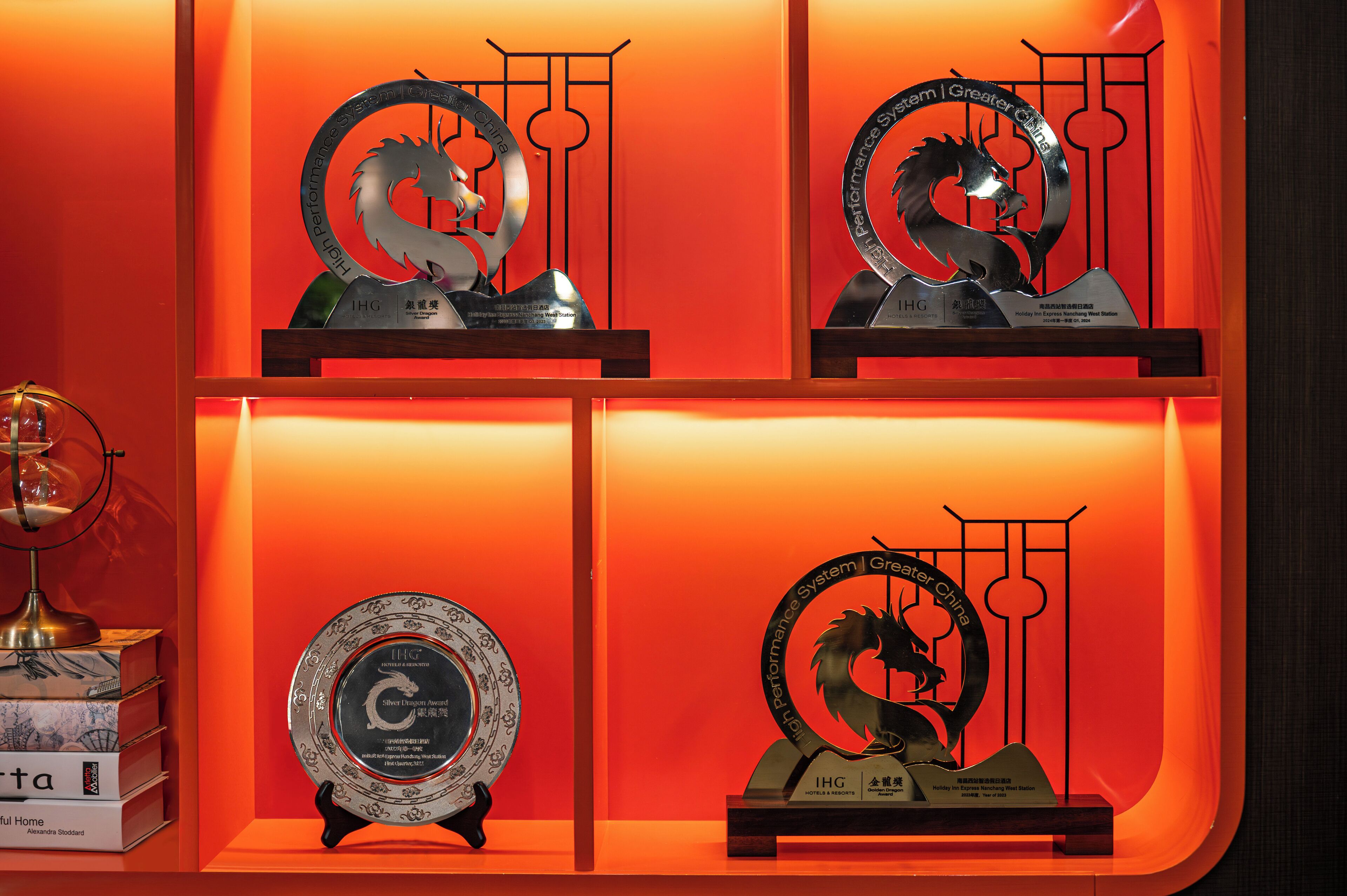 Une collection de trophées exposée sur une étagère, le tout sur un fond rouge.