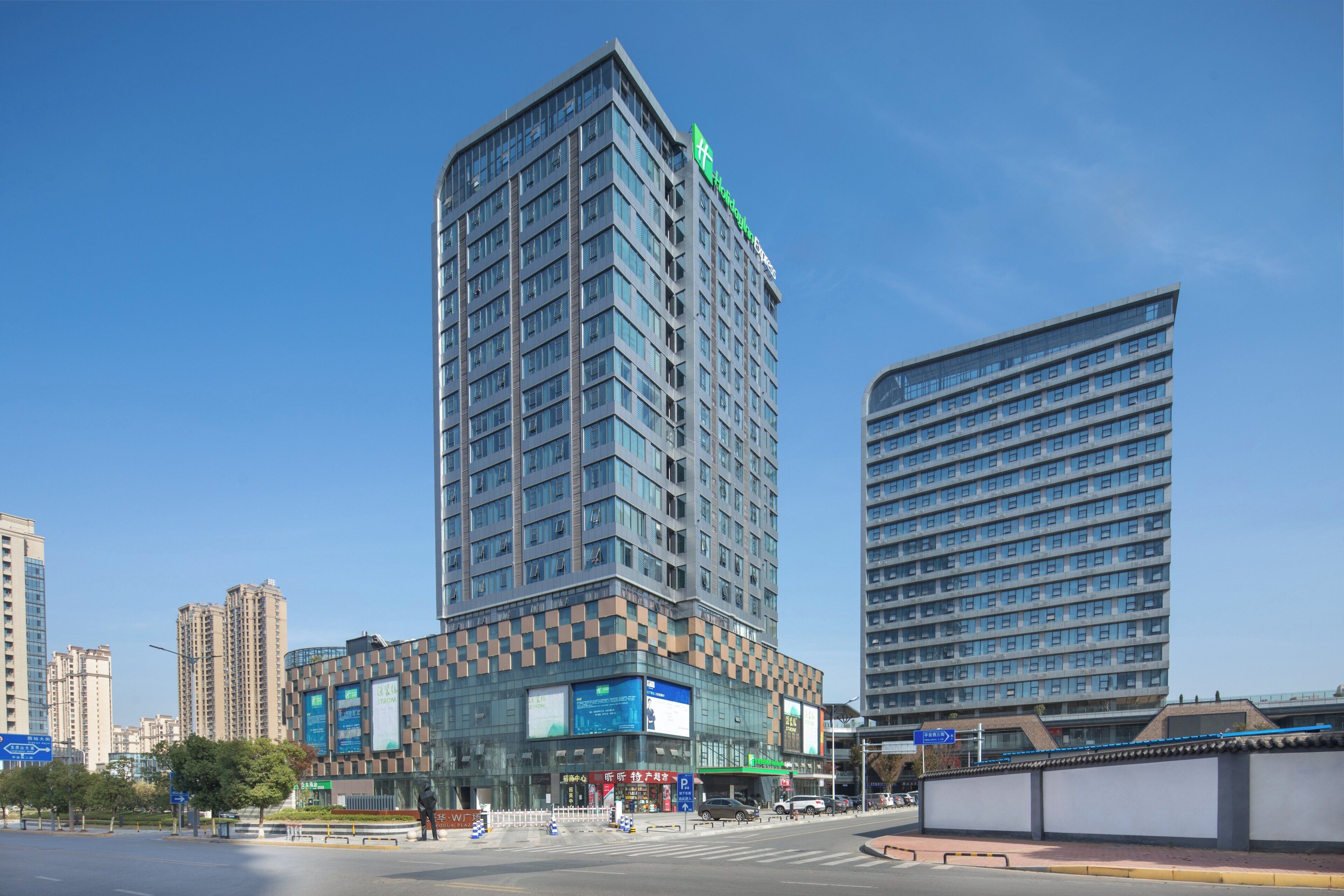A high-rise hotel with a modern design, featuring a prominent green sign at the top.