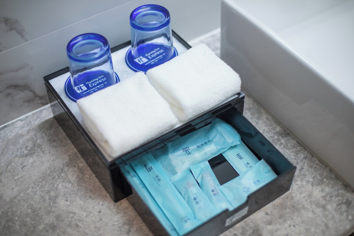 A bathroom with a marble floor, a white bathtub, and a storage box containing toiletries.