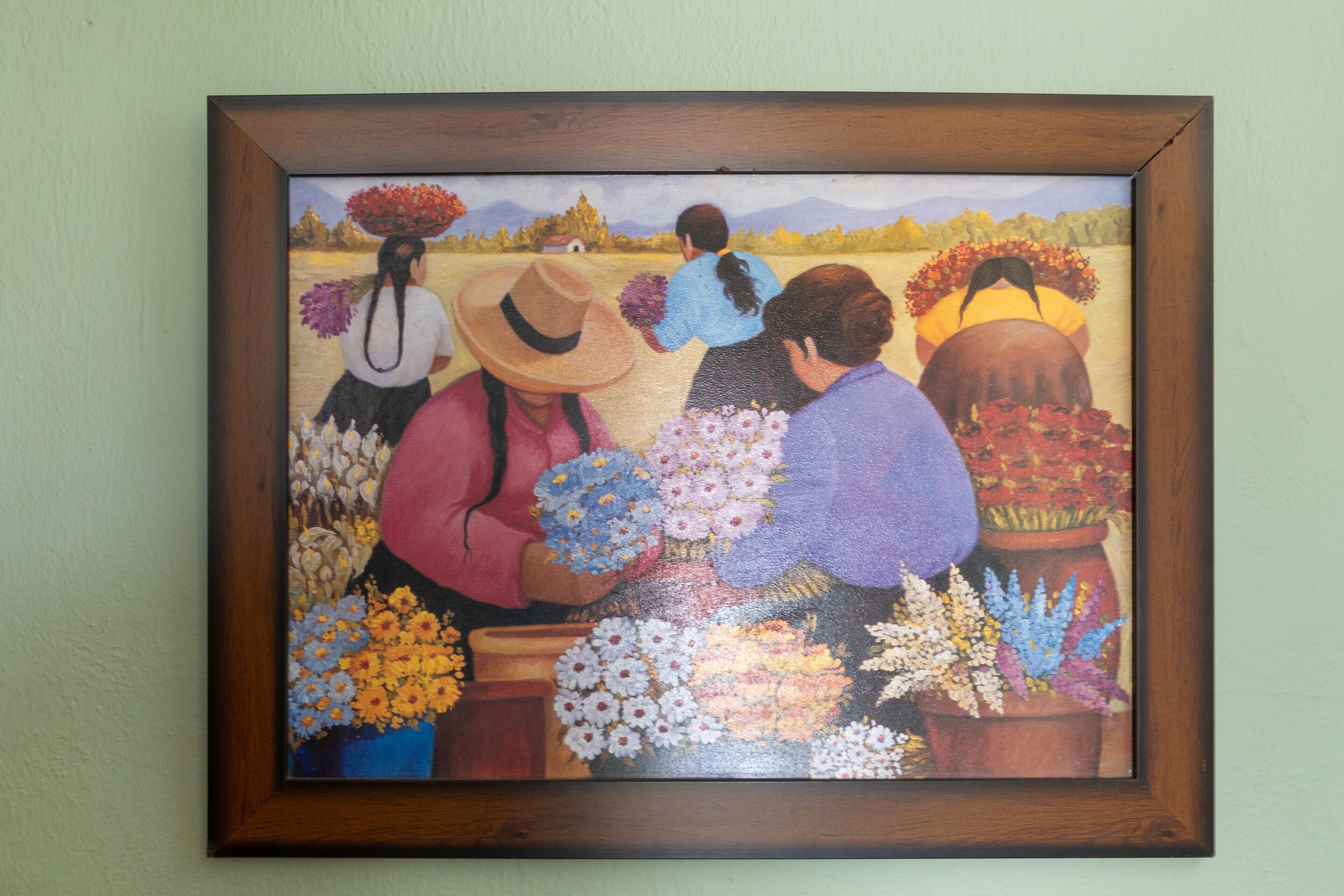 Un tableau encadré représentant trois personnes avec des fleurs.