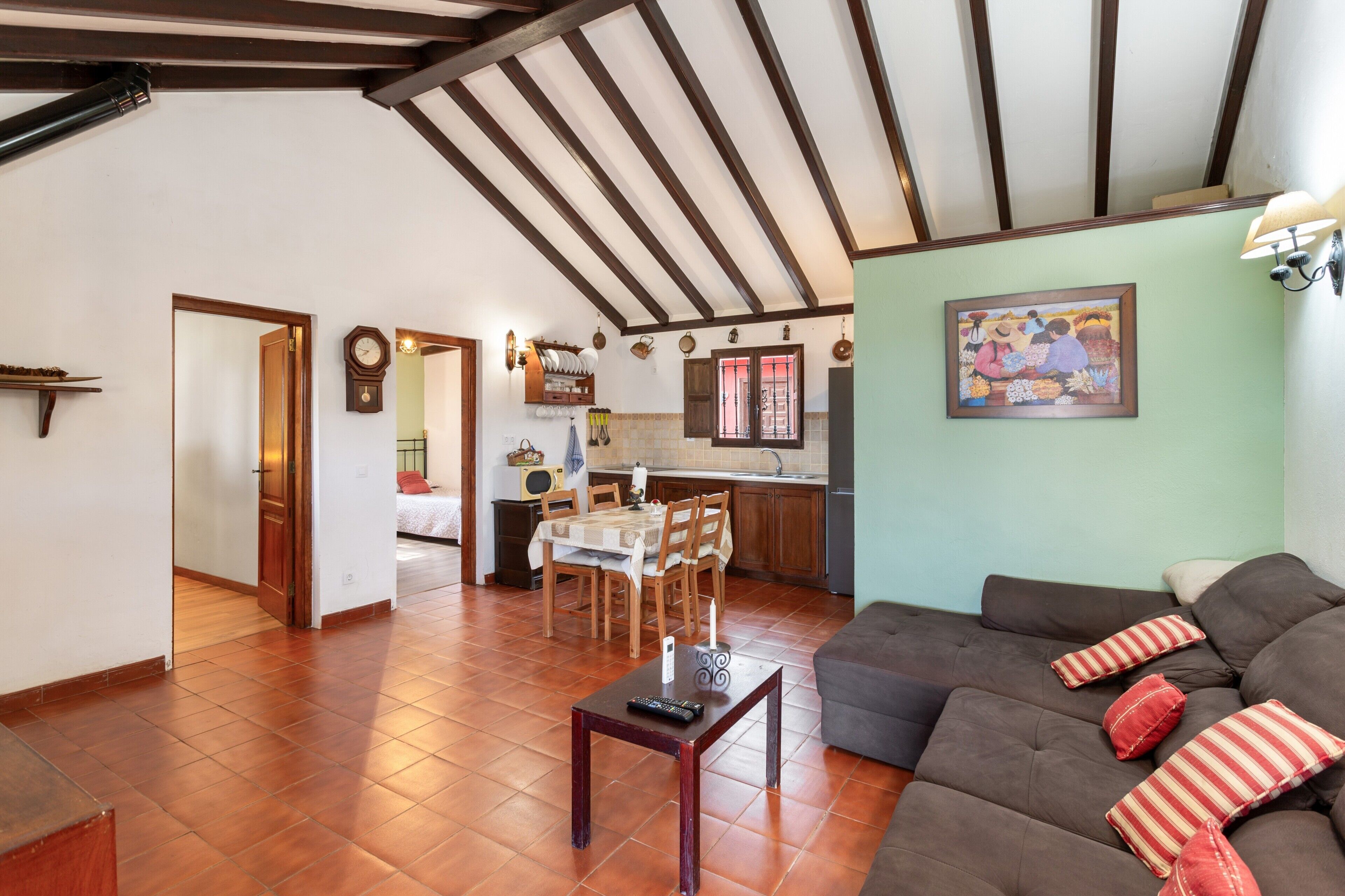 A spacious living area with a dining table, sofa, and kitchen in the background.