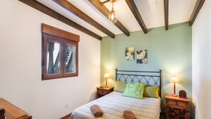 Une chambre à coucher avec un lit, deux tables de chevet, une fenêtre et un plafond en bois.