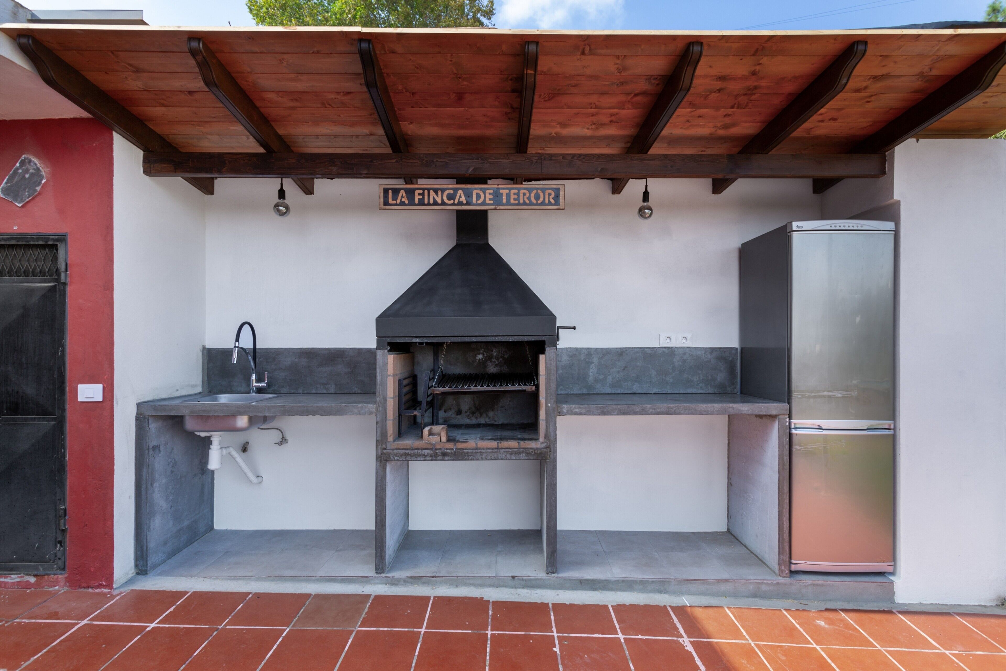 An outdoor kitchen area with a grill, sink, and refrigerator, labeled 'LA FINCA DE TEROR.'