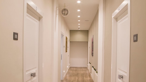 A hallway with wooden flooring, white walls, and doors on both sides. - Garibaldi Rooms (Naples)