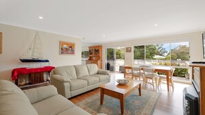 A spacious living room with a beige sofa, a wooden coffee table, and a sailboat model on a red tablecloth. - Sky Mirror Cottage - sleeps 9 (RHYLL)