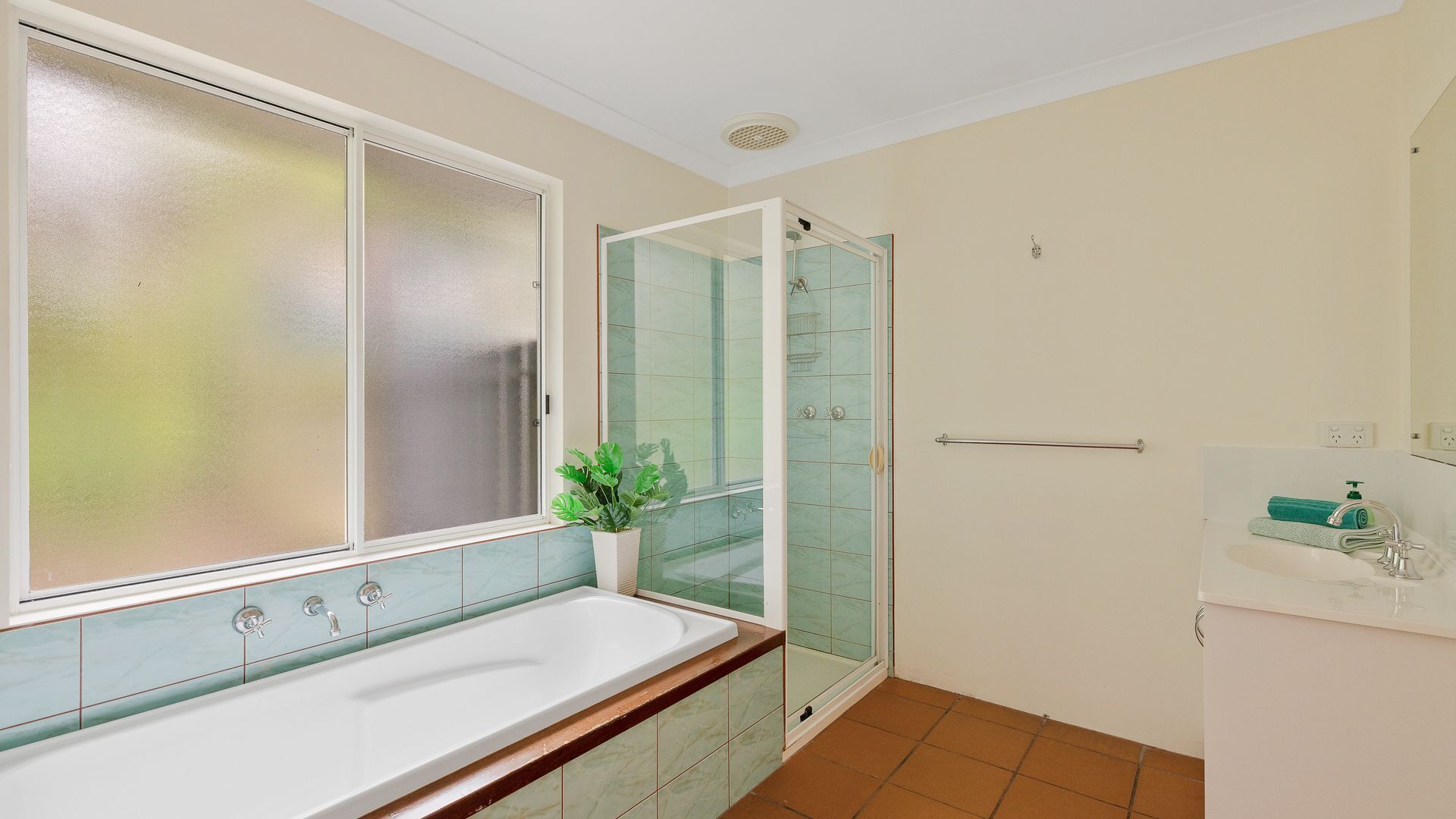 Une salle de bain avec une baignoire, une cabine de douche en verre et une fenêtre à vitrage dépoli.