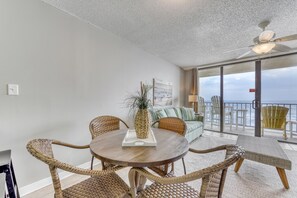 Enjoy ocean views from this balcony with a round table, wicker chairs, and comfortable seating.