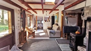 Un salon chaleureux avec une cheminée, un canapé, un fauteuil et un coin repas comprenant une table et des chaises.
