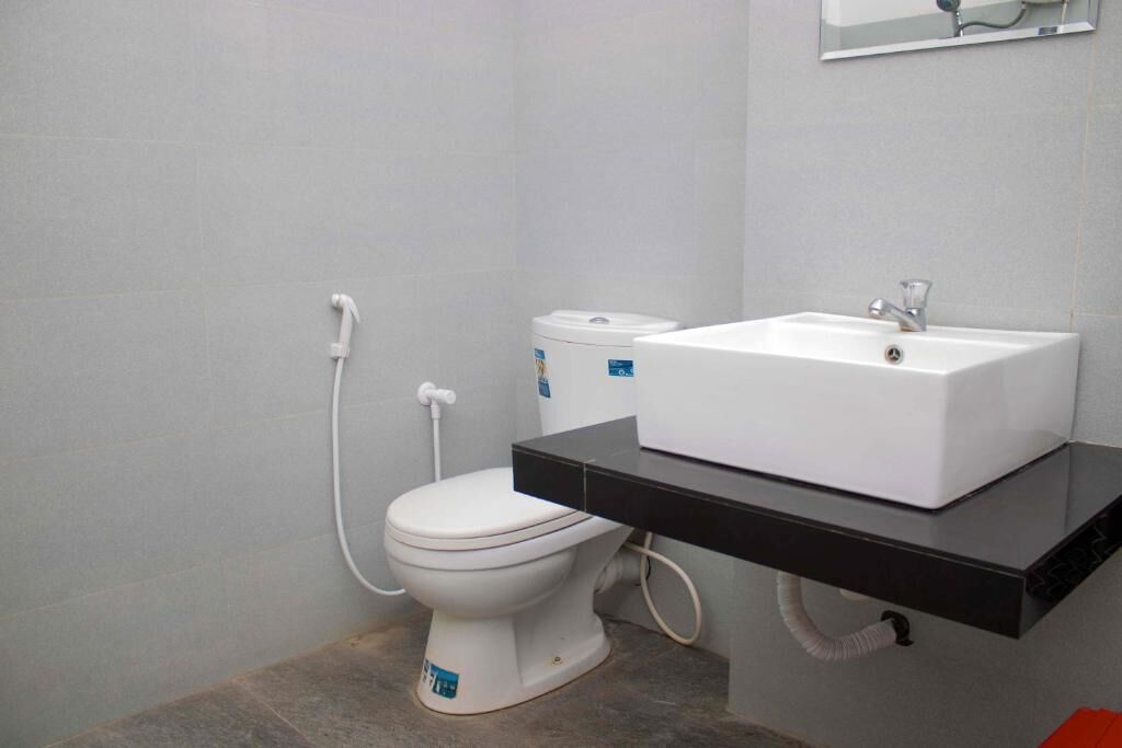 Un baño con inodoro y lavamanos blancos, y encimera negra.