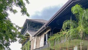 A building with a covered walkway, large planters, and a grassy area. - Sigiriya Kingdom Resort (Dambulla)