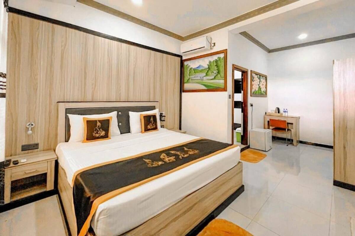 Quarto com cama, mesa de cabeceira e escrivaninha com cadeira.