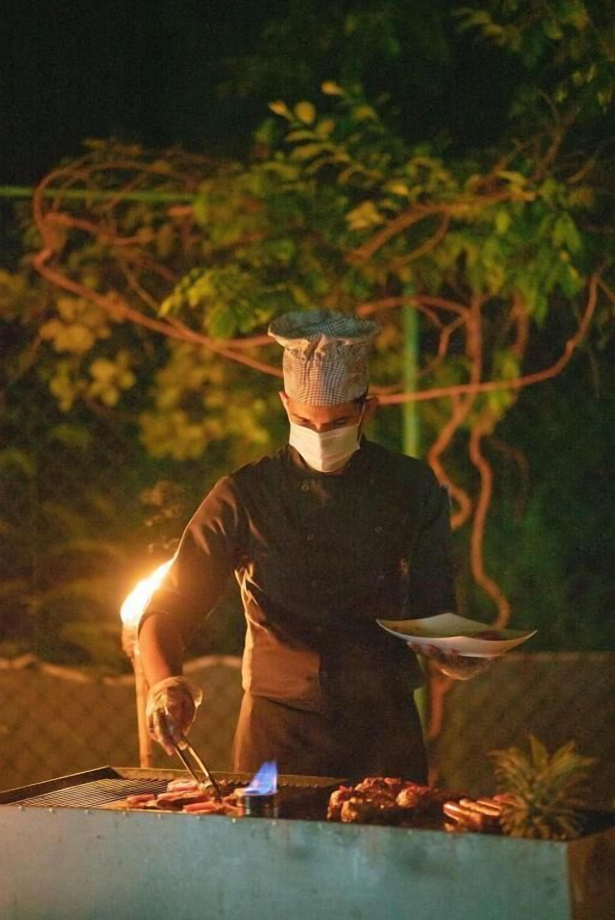 Une personne qui fait griller des aliments sur un barbecue à l’extérieur, la nuit.