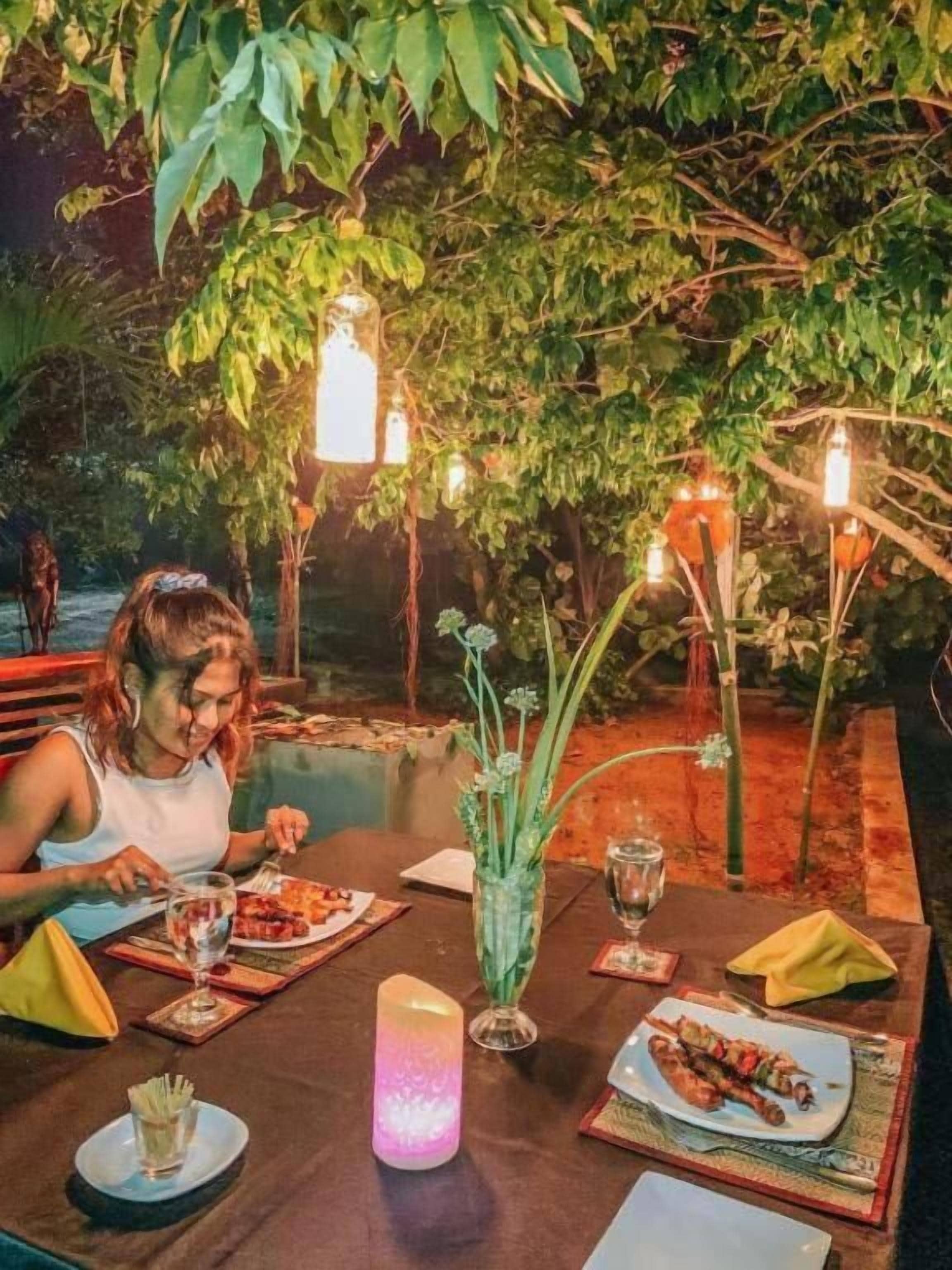 An outdoor dining area with tables, chairs, and ambient lighting.