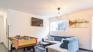 Ein Wohnzimmer mit Kicker, einer Couch, einem Couchtisch und einem Gemälde an der Wand.