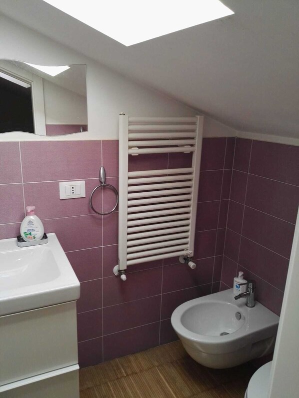 Une salle de bain avec un lavabo blanc, un bidet et un porte-serviettes.