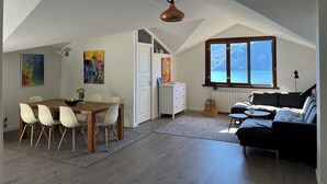 A spacious loft with a dining area, a sofa, and a large window overlooking the sea. - Como Lake view from olive garden, balcony and pool (Tremezzina)