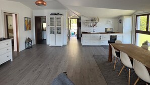 A spacious kitchen with wooden flooring, white cabinetry, and a dining area with a wooden table and chairs. - Como Lake view from olive garden, balcony and pool (Tremezzina)