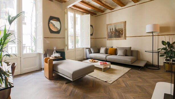 Ein Wohnzimmer mit Sofa, Hocker, Couchtisch und Lampe.