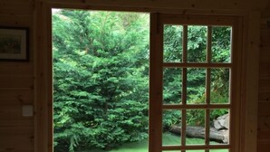 Interior de madeira com uma grande janela que mostra um jardim exuberante lá fora.