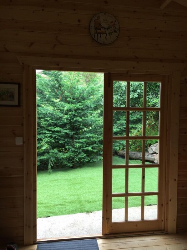 A wooden interior with a large window revealing a lush garden outside.