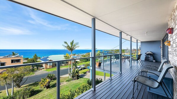 Ein Balkon mit Blick auf den Ozean, ein Grillplatz und eine Rasenfläche mit Palmen.