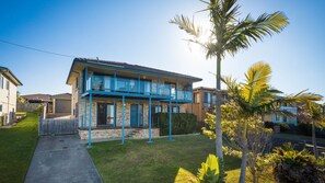 Une maison à deux étages avec un balcon, une pelouse bien entretenue et un palmier.