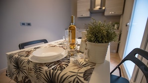 A dining table set with plates, cutlery, a bottle of wine, and a potted plant. - Hotel Rio re (Acquaviva)