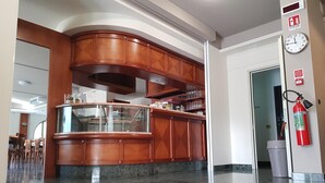 A hotel lobby with a marble floor, wooden reception desk, and a fire extinguisher on the wall. - Hotel Rio re (Acquaviva)