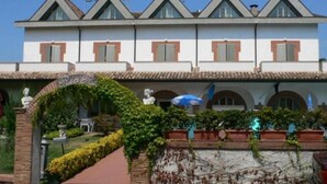 A building with a white facade, multiple windows, and a tiled roof. There is a sign that reads "Rio Re" and a statue in the foreground. - Hotel Rio re (Acquaviva)