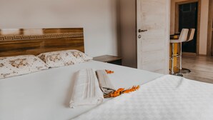 Una cama bien tendida con un cabecero, una mesita de noche y una silla al fondo.