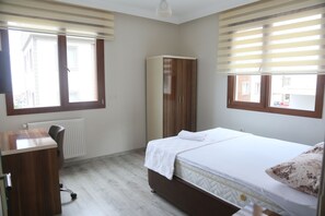 Een slaapkamer met een bed, een kledingkast, een bureau en een radiator.