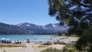 Een strand met een helder uitzicht op bergen in de verte, een pad dat naar het strand leidt en mensen die van de omgeving genieten.
