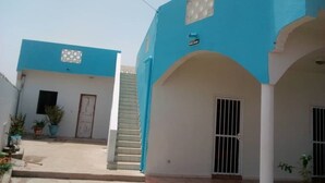 Un edificio con fachada azul, una escalera y una entrada portonada.