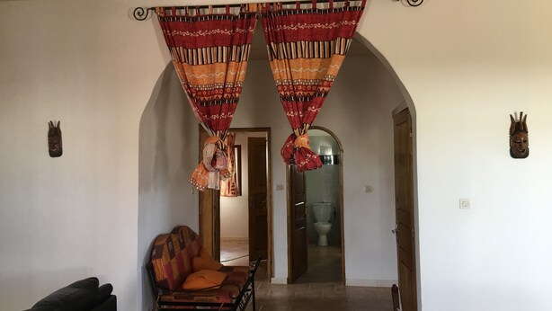 A room with a sofa, a chair, and a wooden bench. There are two doors leading to other rooms.