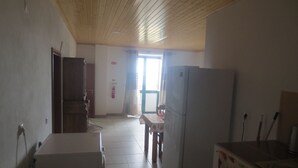 A room with a wooden ceiling, a white refrigerator, a table with a tablecloth, and a door leading to another room. - Villa Lucinda ..... (São João)