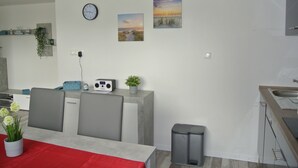 A modern kitchen with a dining area, featuring a clock, artwork, and a small radio. - Holidays, holidays and sea (Wilhelmshaven)